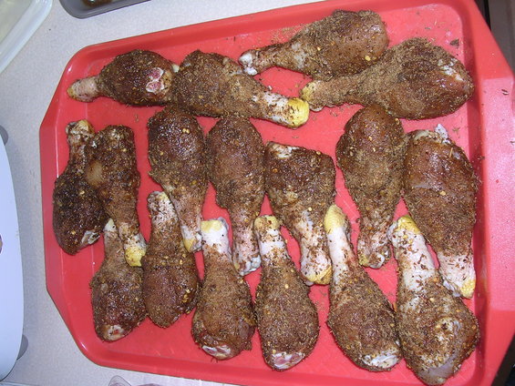 Red tray with seasoned chicken drumsticks arranged in rows