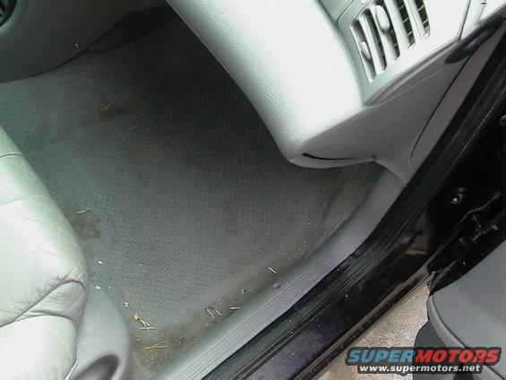 Interior view of a car's passenger side floor and lower dashboard with a vent