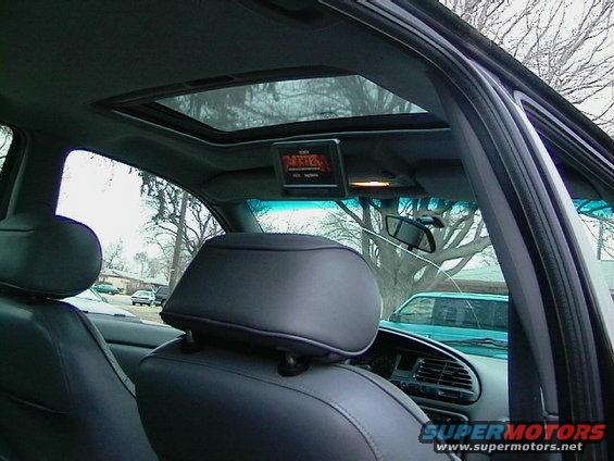 Interior view of car with sunroof and overhead screen displaying 'RASTER'