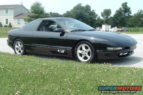 Black 1994 Ford Probe GT parked on grass with a house in the background
