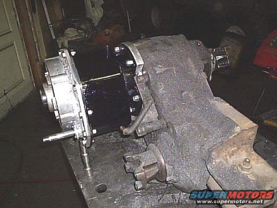 Transfer case with shiny black housing and cast iron section, mounted on a workbench