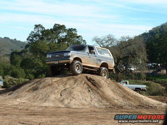 Ford Bronco on a dirt hill, another truck in the background