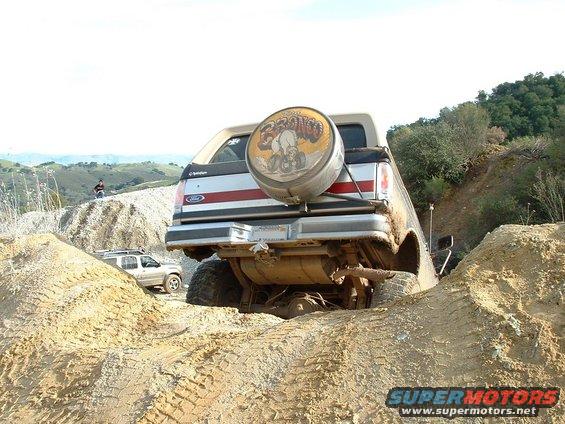 1991 Ford Bronco with spare tire on rear, stuck in dirt off-road