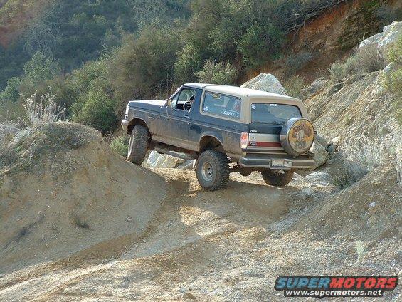 1991 Ford Bronco climbing rocky terrain, spare tire cover features eagle graphic