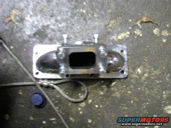 Metal exhaust manifold part with bolts on a concrete surface