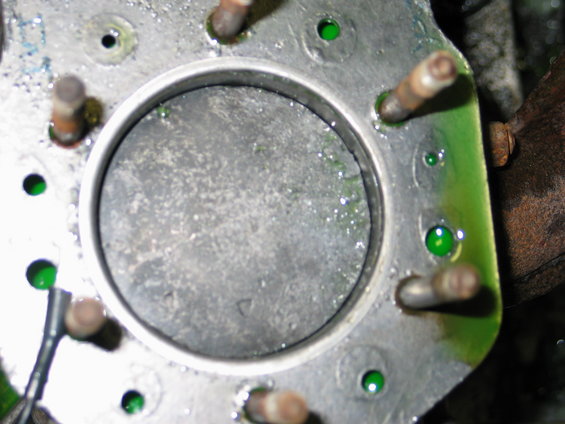 Close-up of an engine cylinder with green fluid pooled around the edges