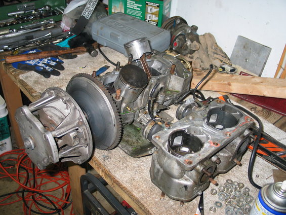 Snowmobile engine block and clutch assembly on a workbench with tools