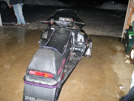 Black Polaris snowmobile with purple trim, viewed from the rear