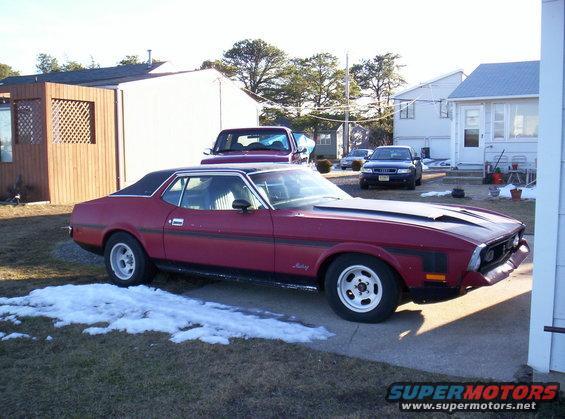 1971 Ford Mustang coupe with a black vinyl roof and hood scoops parked in a driveway
