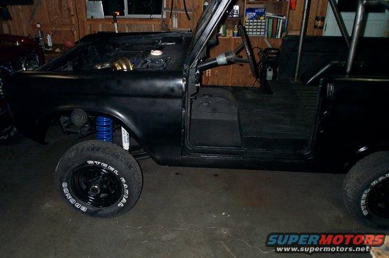 Black 1967 Ford Bronco side view with roll cage and blue suspension