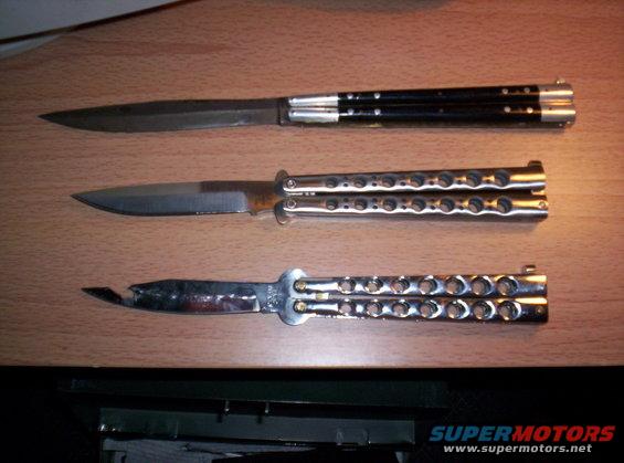 Three butterfly knives laid out on a wooden surface