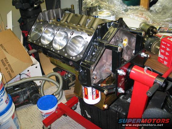 Engine block with cylinders visible, mounted on a red stand with an oil filter attached
