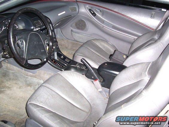 Interior view of a car with gray leather seats and a patterned steering wheel