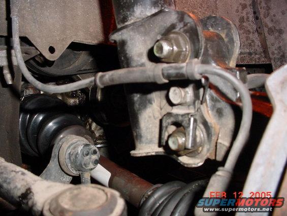 Close-up of a car's front suspension assembly, showing a CV joint boot and shock absorber mount