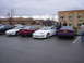 1993 Ford Probe - A group of cars are parked in a lot on an overcast day, with a hotel in the background.