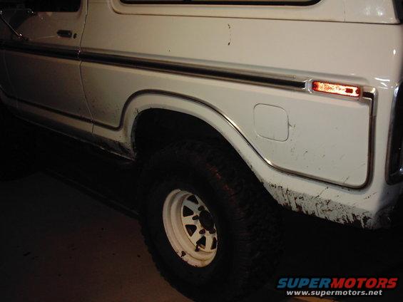 Side view of a white SUV, showing the rear wheel well and fuel door