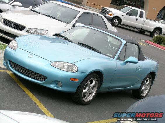 Light blue convertible sports car, front view. Likely a Mazda Miata