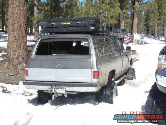 Rear view of silver SUV stuck in snow, with a Husky toolbox on roof rack