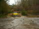 1990 Ford Bronco - A yellow pickup truck navigates a challenging muddy terrain, kicking up a significant spray.