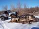 1974 Ford Bronco - A blue Bronco is parked on top of two heavily damaged cars in a snowy, wooded area.
