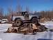 1974 Ford Bronco - A light blue Ford Bronco is perched atop two heavily damaged cars in a snowy, outdoor setting.