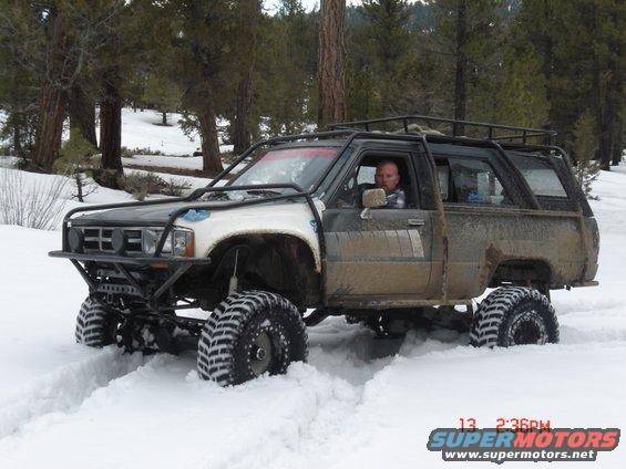 Off-road SUV with big tires driving through snow, driver visible