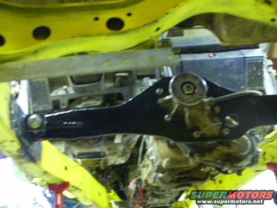 Underside of a yellow vehicle with black suspension components and a visible transmission