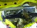 1990 Ford Bronco - Underside view of a vehicle's yellow frame and black suspension parts, with a transmission visible.