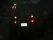1990 Ford Bronco - This SUV's rear lights are illuminated while driving on a dark, wet road, with another vehicle in front.