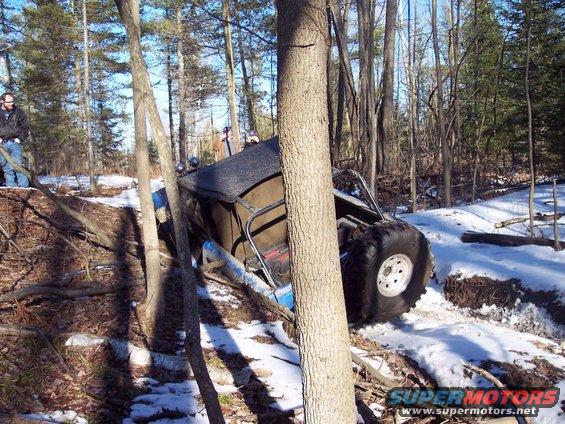 Off-road vehicle tilted in snowy woods, large tires visible