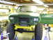 1990 Ford Bronco - This green SUV is undergoing repairs in a garage, with its front end removed and tires elevated.