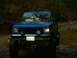 1990 Ford Bronco - This blue pickup truck is navigating through a watery, wooded area.
