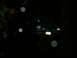 1990 Ford Bronco - A blue SUV is parked in the dark, illuminated by its headlights and some circular light artifacts.