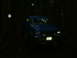 1990 Ford Bronco - Blue pickup truck driving off-road at night in a wooded area. The vehicle appears to be from the 1980s.