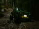 1990 Ford Bronco - Off-road truck driving through a challenging, muddy, and rocky path in a dense forest.