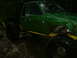 1990 Ford Bronco - This heavily modified truck sits in a wet, wooded environment, its large tires covered in mud.