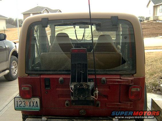 Red Jeep Wrangler rear view with tan hardtop, spare tire mount, and license plate 123 XXA