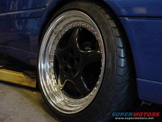 blue car's custom black five-spoke wheel with polished lip and low-profile tire