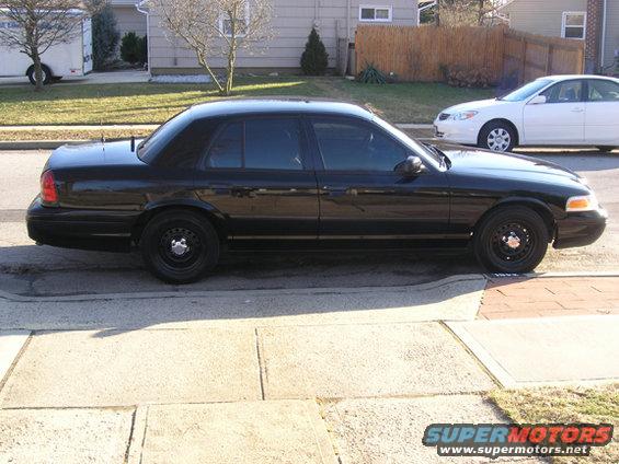 Black sedan parked on street, white sedan in background