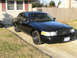 1999 Ford Crown Victoria - This 1999 Ford Crown Victoria is captured in a 3/4 front view, its black grille and steel wheels.