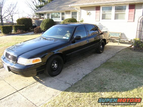 Black Ford Crown Victoria parked in a driveway. The car has steel wheels and tinted windows