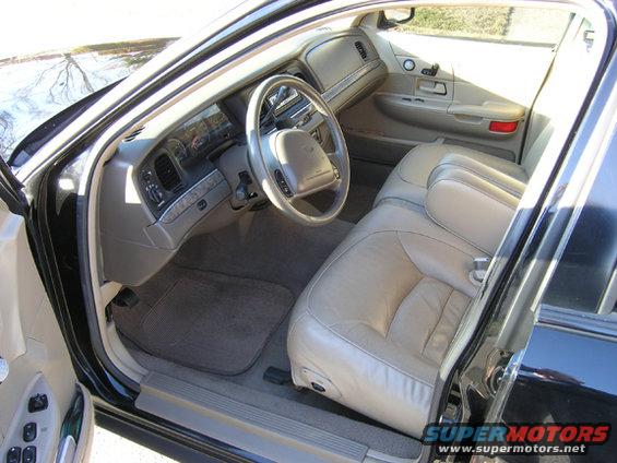 Interior of a 1999 Ford Crown Victoria, showing tan leather seats, dashboard, and steering wheel