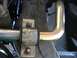 1999 Ford Crown Victoria - Close-up view of a sway bar and its mounting bracket, part of a vehicle's suspension system.