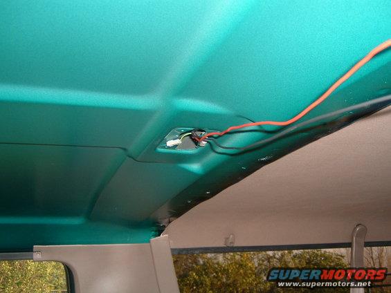 Interior view of vehicle headliner with exposed wiring and connectors