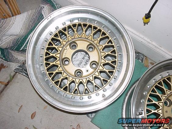 Gold mesh car wheel with silver lip and bolts, viewed from front