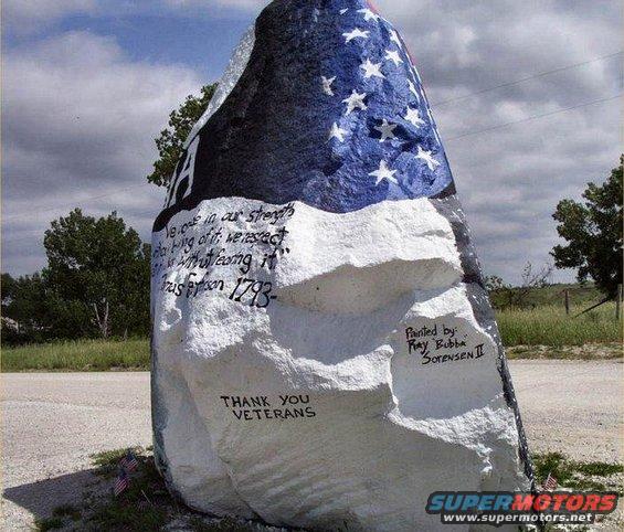 Large rock painted with American flag, stars, and patriotic text