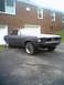 1968 Ford Mustang - A dark gray 1967 Ford Mustang coupe is parked in front of a brick building, its front bumper missing.