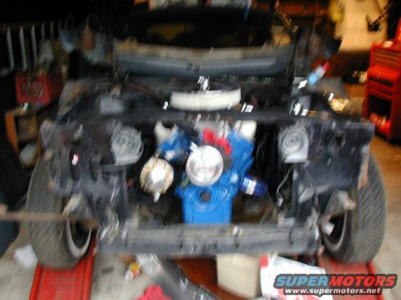 1968 Ford Mustang engine bay with blue engine, air filter, and exposed front end