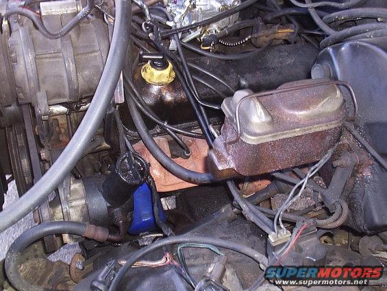 Engine bay with visible oil filter, brake fluid reservoir, and carburetor