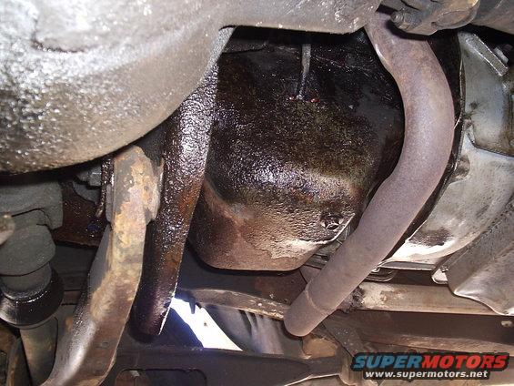 Underside view of oily engine pan and exhaust pipe